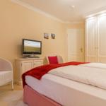 Bedroom with double bed, TV, white chairs, and wardrobe.