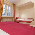 Bedroom with large bed and small bed in recessed area.