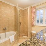 Bathroom with bathtub, shower, and sink with marble countertop.