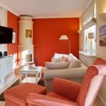 Living room with red wall, sofa, armchair, and fireplace.