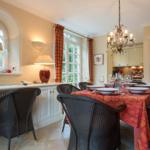 Dining room with set table, wicker chairs, and windows with curtains.