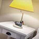 Tischlampe mit Entenfigur auf weißem Nachttisch