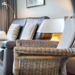 Ein Wohnzimmer mit Ledersofa, Kissen und einem Stuhl mit geflochtenem Sitz.