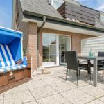 Terrasse mit Strandkorb und Tisch mit Stühlen vor einem Haus