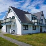 Modern house with balconies and bicycle. Green lawn and clear view.
