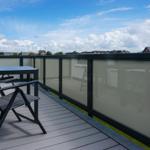 Terrace with table, chairs, and privacy screen. View of residential area under blue sky.