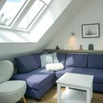 Living room with skylights, blue sofa, and gray armchair.