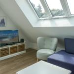 Living room with TV, seating, and skylight.