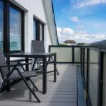 Terrace with table and two chairs, view of buildings and sky.