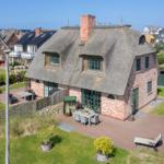 Dorfhaus mit Strohdach und Gartenbereich mit Terrasse.