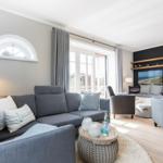 Wohnzimmer mit grauem Sofa, Fernseher und Blick auf Terrasse.