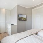 Schlafzimmer mit Bett, Kleiderschrank und Fernseher an der Wand.
