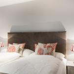 Schlafzimmer mit Bett, Kissen und Nachttischen mit Lampen.