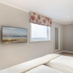 Schlafzimmer mit Bett, TV und Fenster mit Vorhang.