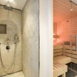 Dusche mit Steinwand und Sauna mit Holzbank.