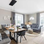 Essbereich mit Tisch und Stühlen, Wohnbereich mit Sofa und Fenster.