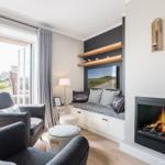 Wohnzimmer mit Kamin, Sitzbank und Fenster zur Terrasse.