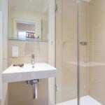 Badezimmer mit Dusche, Waschbecken und Heizkörper