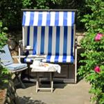 Blau-weiße Strandliege mit Tisch und Stühlen im Garten.