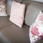 Ein Sofa mit drei Kissen, zwei mit Korallenmuster, eines mit Streifen.
