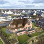 Village house with thatched roof and terrace in quiet residential area.