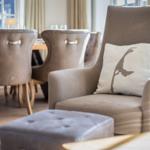 An armchair with a cushion and a table with chairs in the room.