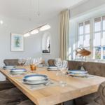 Dining room with wooden table, chairs, and window view.