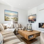 Living room with sofa, fireplace, and TV mounted on the wall.