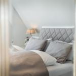 Bedroom with bed, pillows, and bedside lamp under sloped ceiling