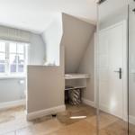 Bathroom with shower, window, and seating area under sloped ceiling.