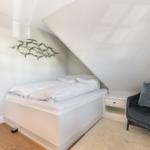 Bedroom with sloped ceiling, bed, and armchair.