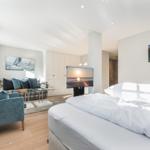 Bedroom with bed, TV, and seating. Wall art shows beach and sailboat.