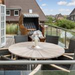 Terrace with round table and chairs, lounge chair, and view of rooftops.