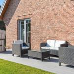 Terrasse mit Sitzgruppe und Liegestuhl vor Backsteinhaus