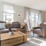 Wohnzimmer mit Ledersofa, Holztisch und Blick auf den Garten.