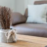 Holztisch mit Deko-Topf und Sofa im Hintergrund