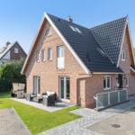 Modern brick house with terrace and garden. Black roof, white windows.
