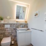 Bathroom with sink, toilet, and lit mirror