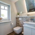 Bathroom with sink, toilet, and window with view.
