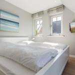 Bedroom with double bed, two windows, and wall art.