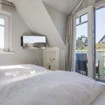 Bedroom with dormer window, TV, and balcony with seating.