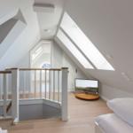 Attic room with sofa bed, TV, and skylights.
