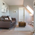 Living room with brown sofa, wooden table, and sloped ceiling.