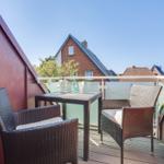 Terrace with table and two chairs, view of residential houses.