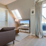 Living room with sofa, TV, and balcony door. Skylight and light wooden floor.