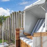 Eine Strandkörbe mit Streifenkissen und Holzrahmen im Garten.