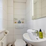 Badezimmer mit Waschbecken, Spiegel und Toilette. Dekorative Fische und Segelboot.