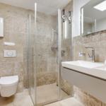 Badezimmer mit Dusche, Waschbecken und Toilette. Wandfliesen und Spiegel.