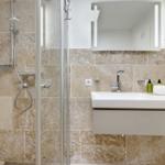Badezimmer mit Dusche, Waschbecken und Spiegel