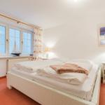 Schlafzimmer mit Bett, Nachttisch, Fenster und Vorhang.